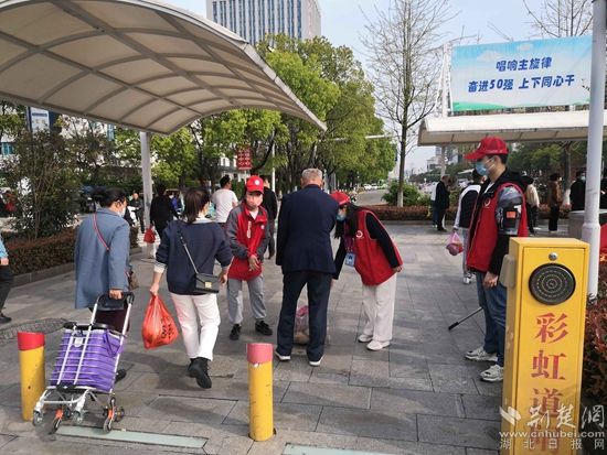志愿服務(wù)隊(duì)在人民醫(yī)院路口開展文明交通體驗(yàn)活動(dòng)，并幫助老人提重物.jpg.jpg